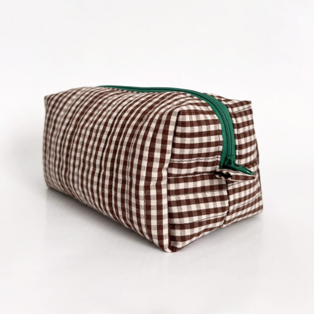 Trousse en tissu à carreaux marron et blanc, avec une fermeture zippée verte