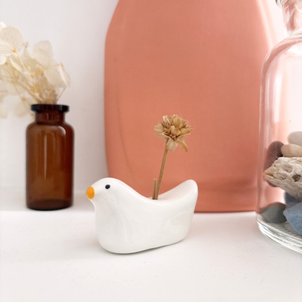 Soliflore en céramique blanche en forme de mouette, avec une fleur séchée
